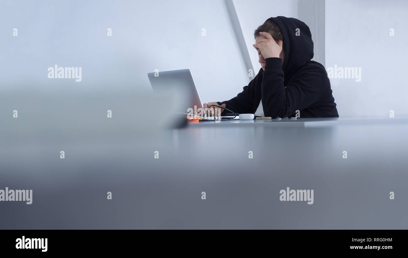 Cyber security concept. yber criminals background. Student preparing to exam. Female working at office. Female in hood sitting at table. Student Stock Photo