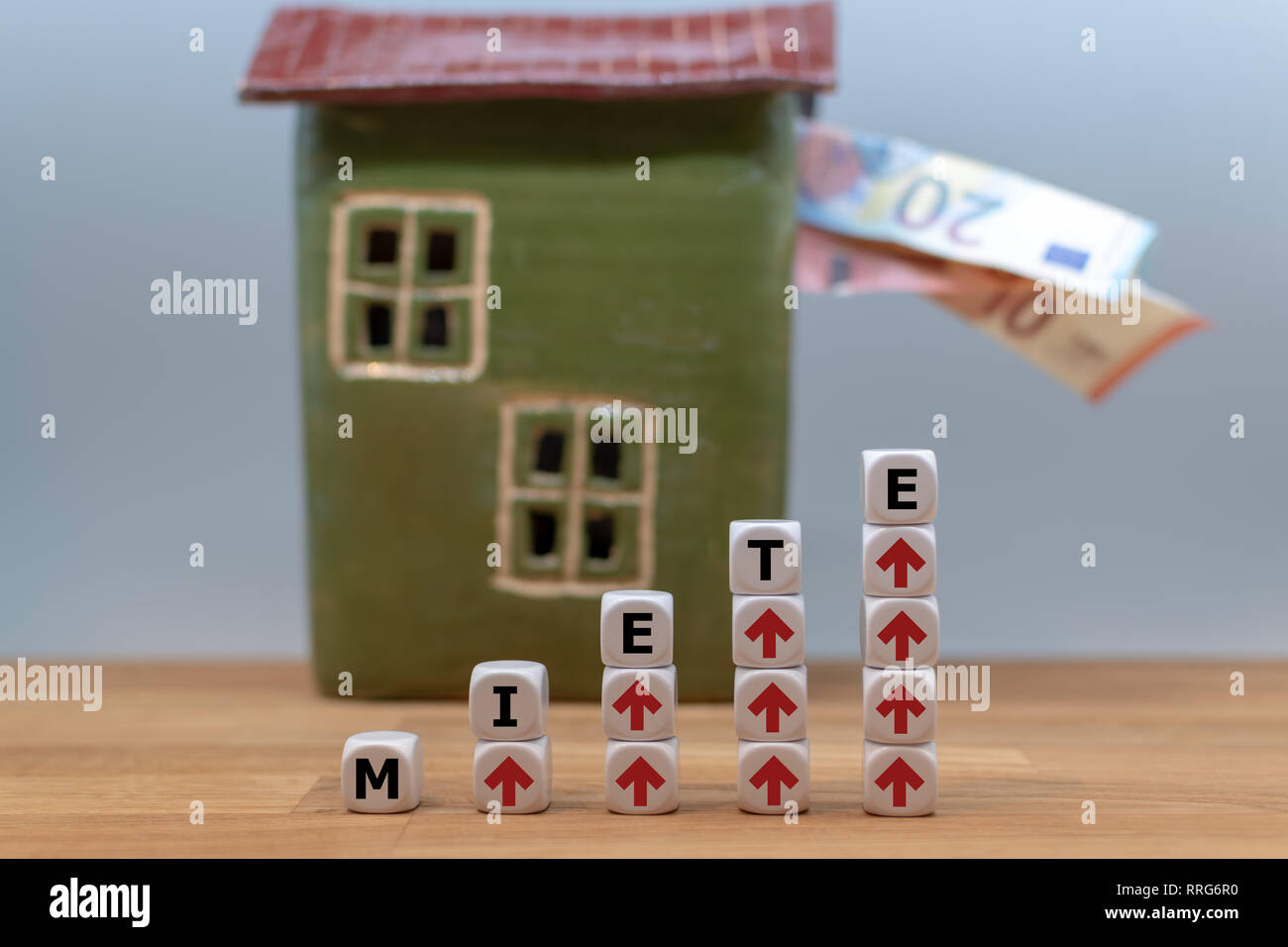 Symbol for rent increases. Dice form the German word 'Miete' ('rent' in English) in front of a model house. Stock Photo