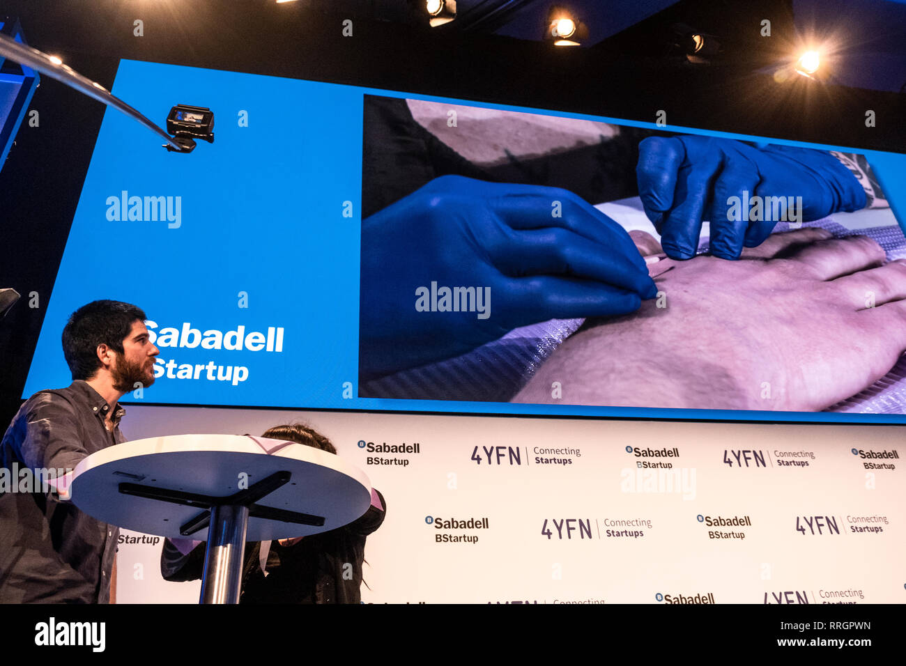 A volunteer Edgar Pons  is seen speaking during the Live Human Chip Implant Show.  Edgar Pons has been implanted with an RFID chip in his hand. Minutes later he has ordered a bank transfer (Banco Sabadell)  using his hand as an authorization signature. In parallel to the MWC, Barcelona celebrates 4YFN Connecting Startups a fair of small business initiatives connected by technology. Stock Photo