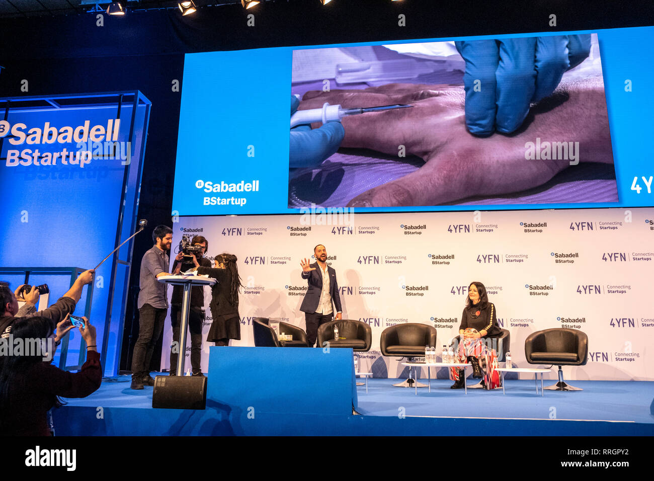 A volunteer Edgar Pons  is seen speaking during the Live Human Chip Implant Show.  Edgar Pons has been implanted with an RFID chip in his hand. Minutes later he has ordered a bank transfer (Banco Sabadell)  using his hand as an authorization signature. In parallel to the MWC, Barcelona celebrates 4YFN Connecting Startups a fair of small business initiatives connected by technology. Stock Photo