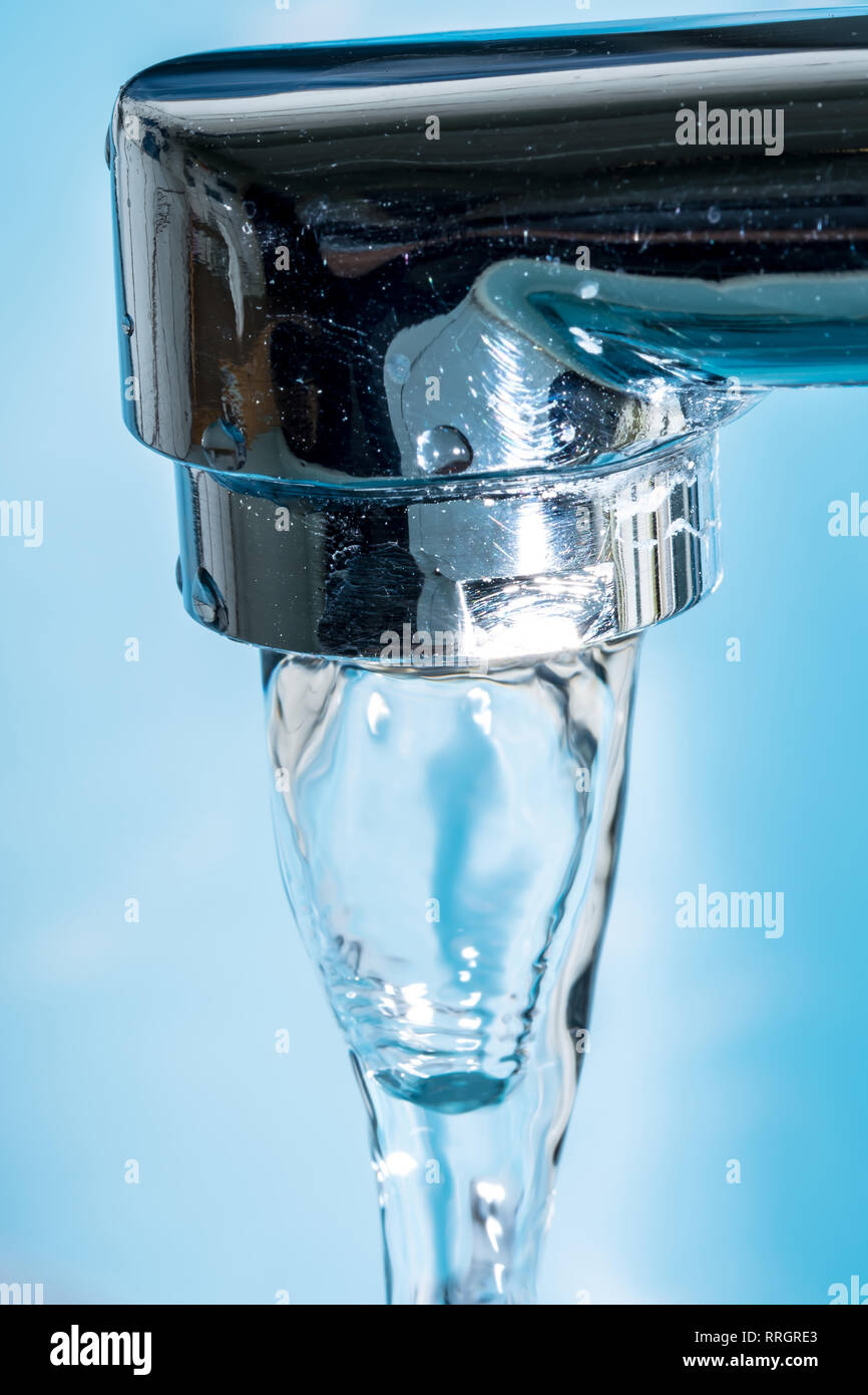 Water flows from a modern chromed water tap faucet macro close-up. Stock Photo