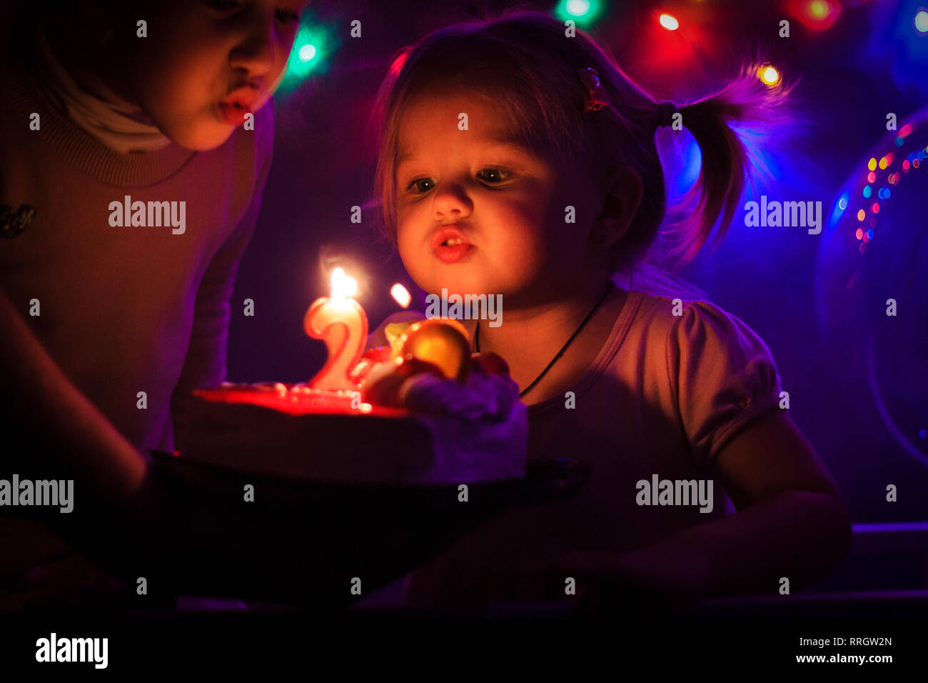 little girl blowing out candles on a birthday cake, holidays Stock