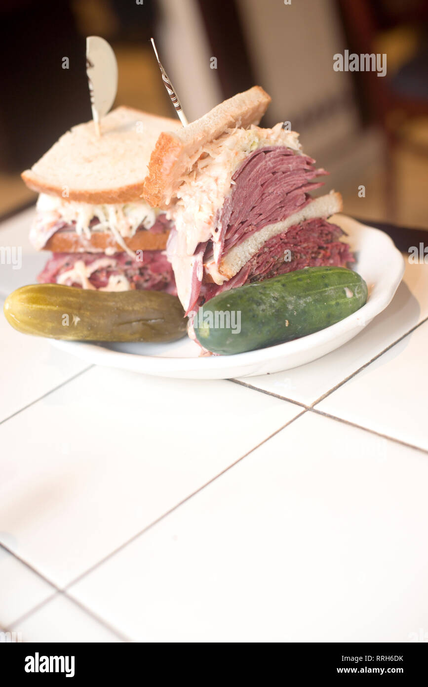 Kosher deli combination sandwich pastrami corned beef tongue cole slaw and Russian dressing on seeded Jewish rye bread with garlic and sour pickles Ne Stock Photo