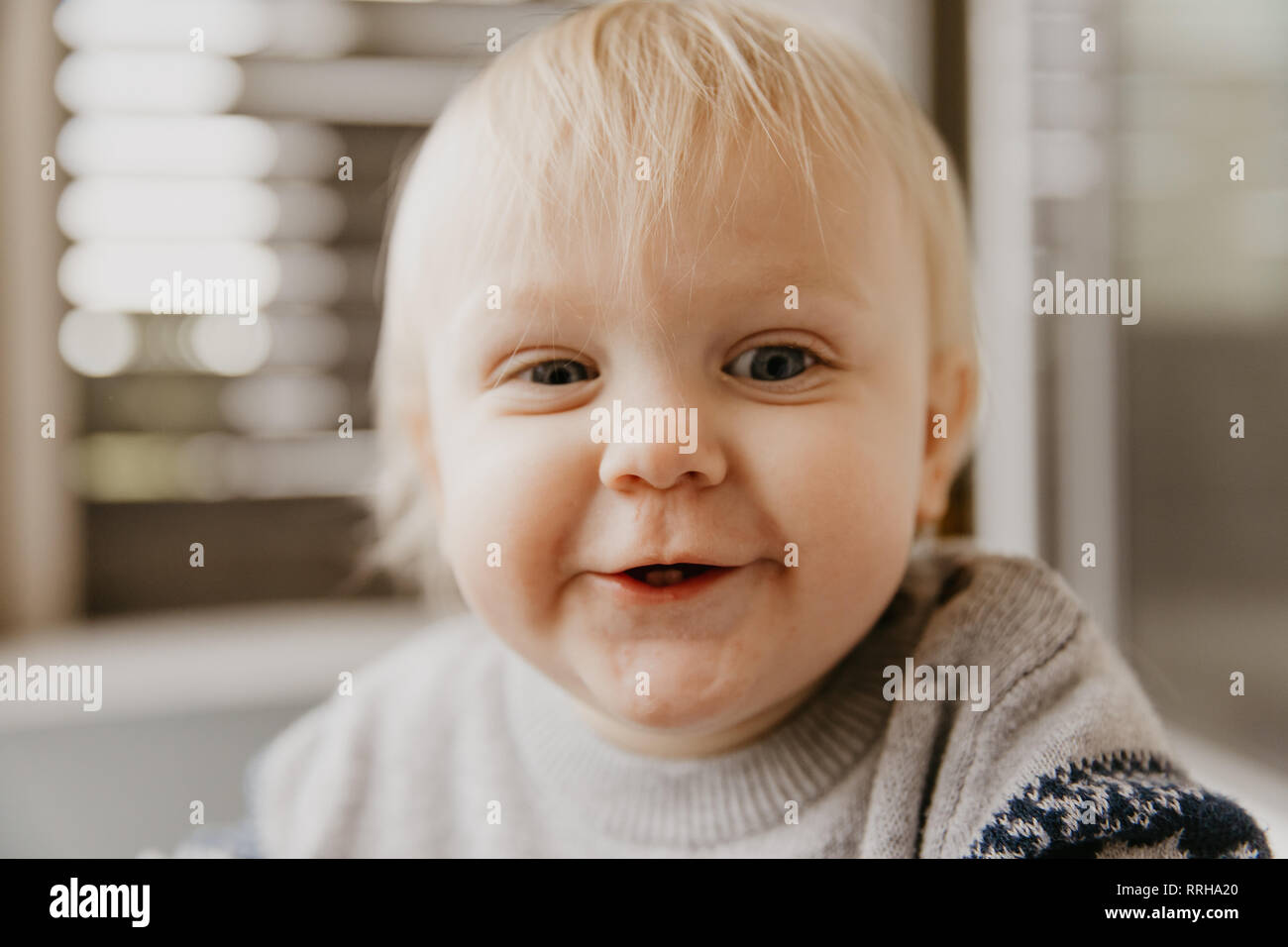 Cute Adorable Little Blonde Toddler Kid Laughing, Having Fun, and Making Silly Faces Outside at Home on the Patio Screened  Porch Stock Photo