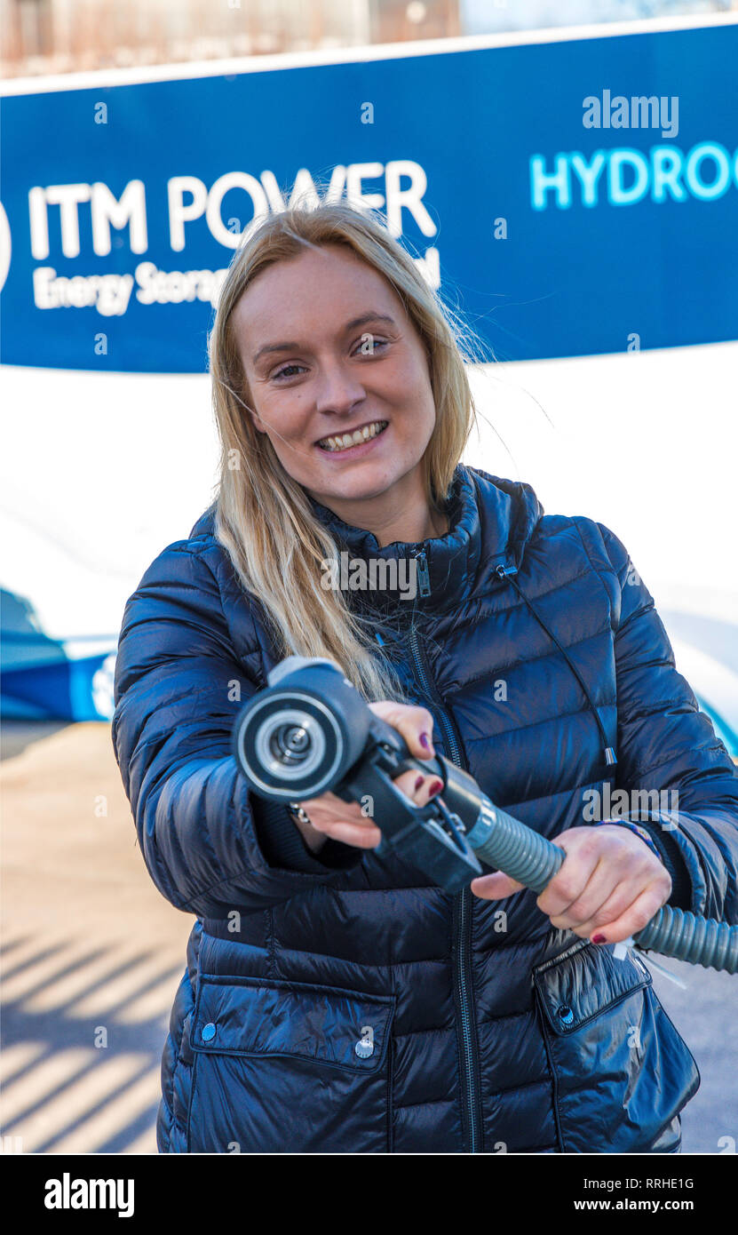 Woman smiling holding a refuelling hose for Hydrogen cars. Fast Refuelling with hydrogen takes just three minutes. Stock Photo