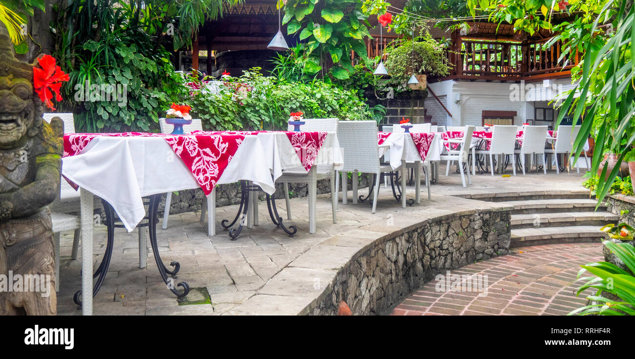Restaurant tables set in a garden courtyard Kuta Bali Indonesia. Stock Photo