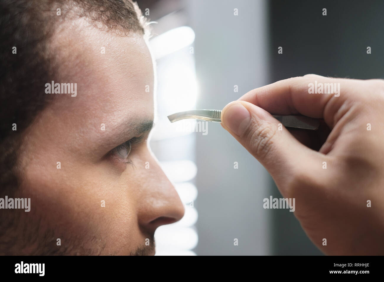 Closeup Of Male Face Man Plucking Eyebrow Hair For Beauty Stock