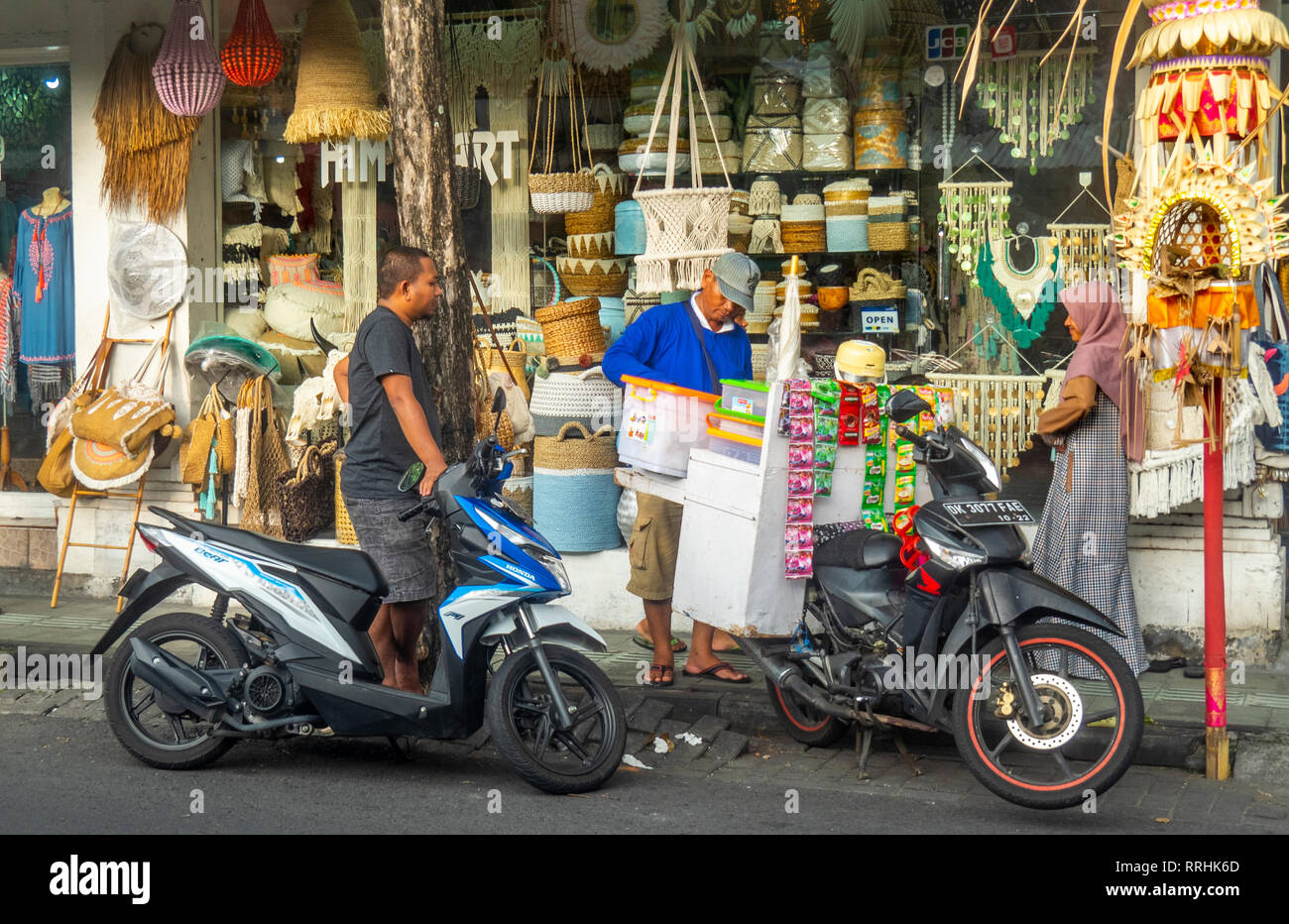 Man loading goods onto a motorbike in Kuta, Bali, Indonesia. Stock Photo