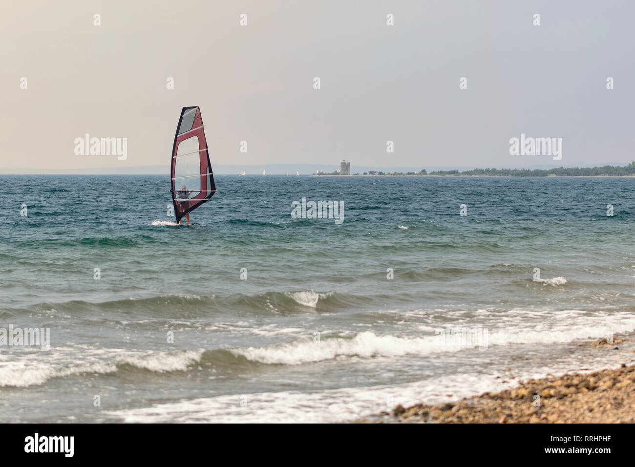 Windsurfing on vacation in a calm sea. A lonely woman on a windsurfing