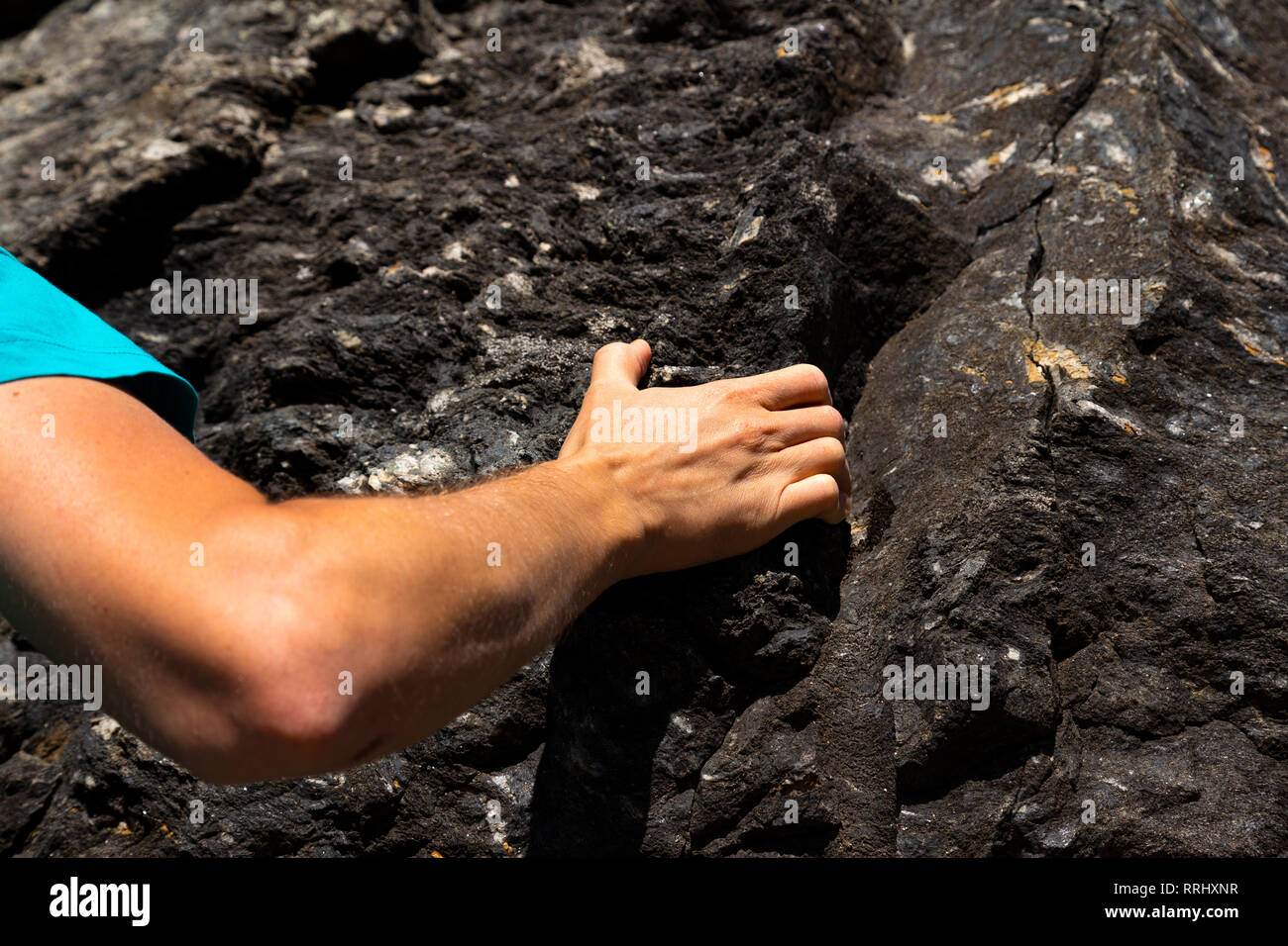 Hand of a young caucasian man climbing on a rock in Switzerland Stock Photo
