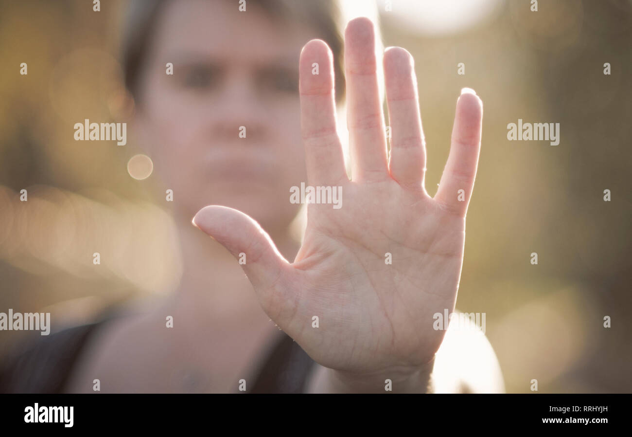 A woman holds up her had to indicate 'stop' or 'peace and desist' on a summers day. Stock Photo