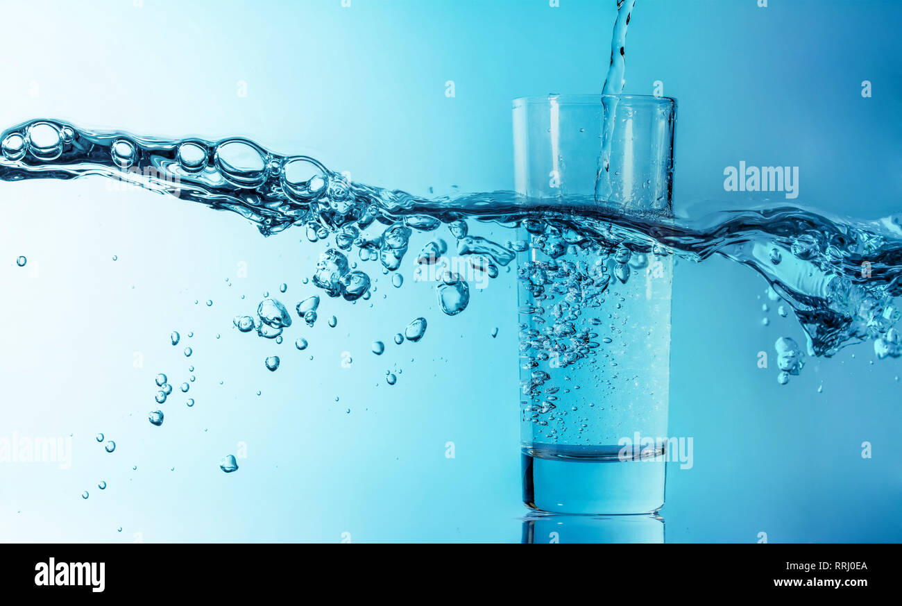 Blue water splash pours into a glass on a beautiful blue sea wave background.  Glass of clean drinking blue water with bubbles Stock Photo - Alamy