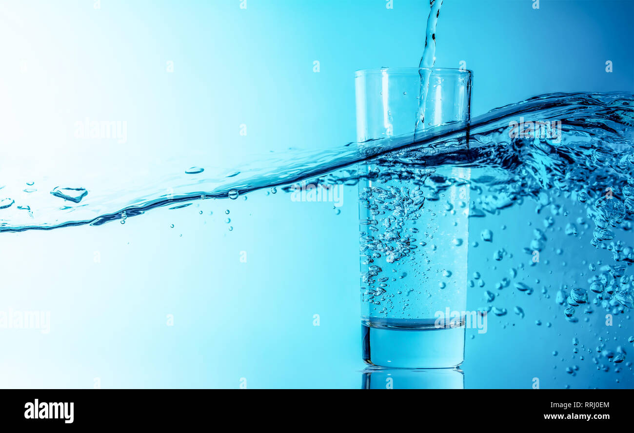 Blue water splash pours into a glass on a beautiful blue sea wave
