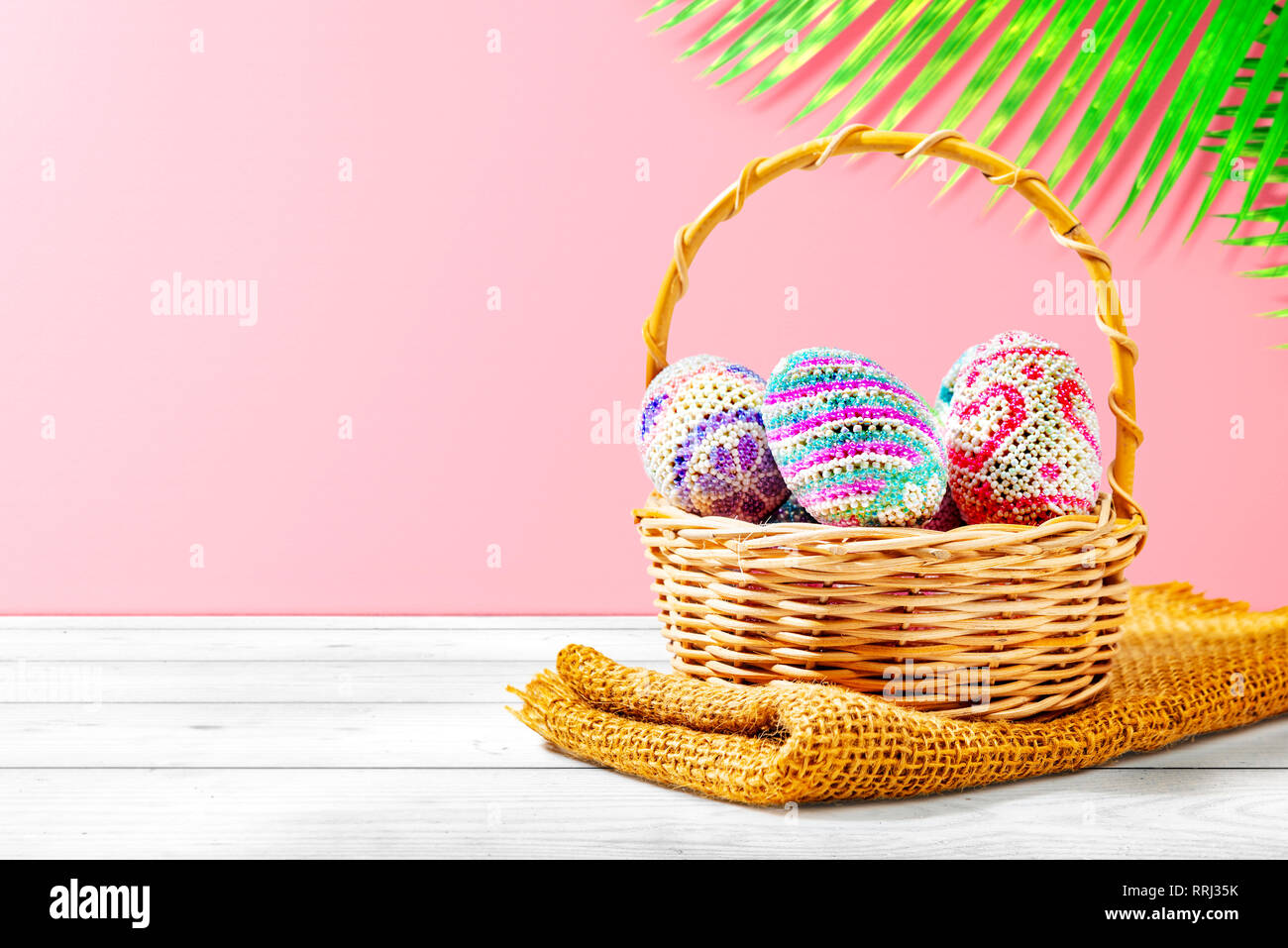 Colorful easter eggs in wooden basket with fabric on wooden table with ...