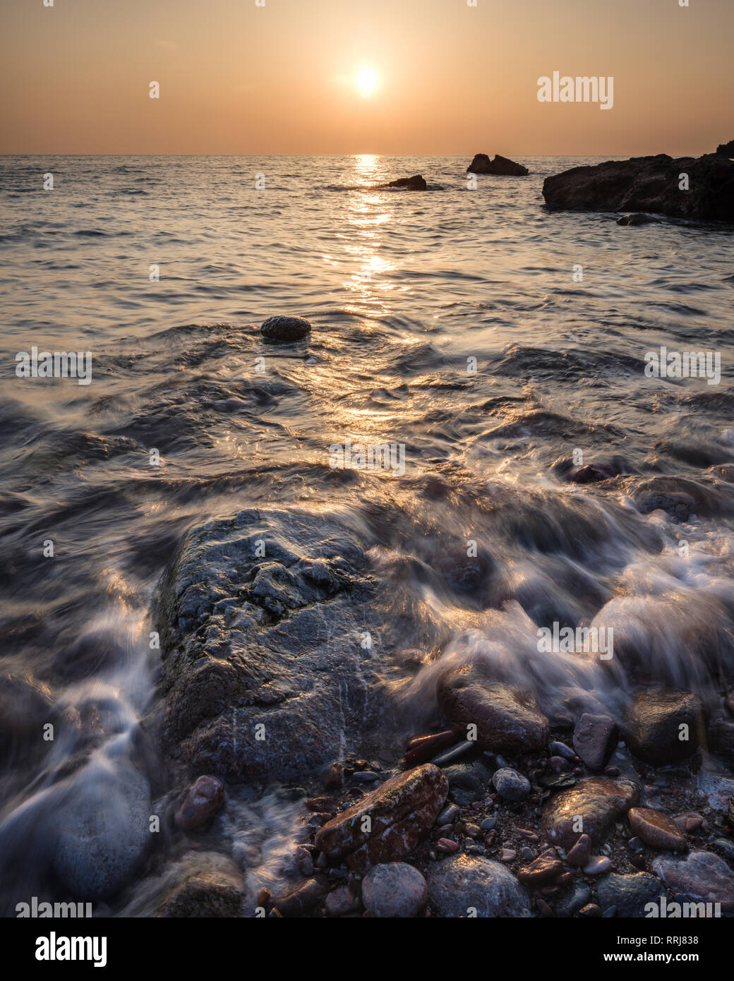 A colourful sunrise over Torbay with warm light glinting off the wave