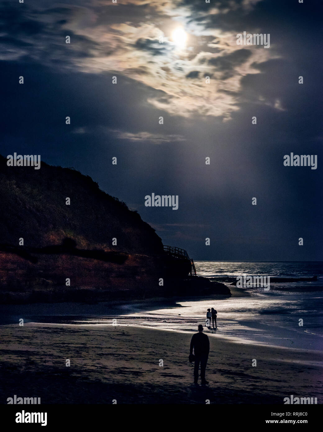 Someone observes two ladies whilst watching the full Blood Moon, shortly after an eclipse at Orcombe Point, Exmouth, Devon, England, United Kingdom Stock Photo