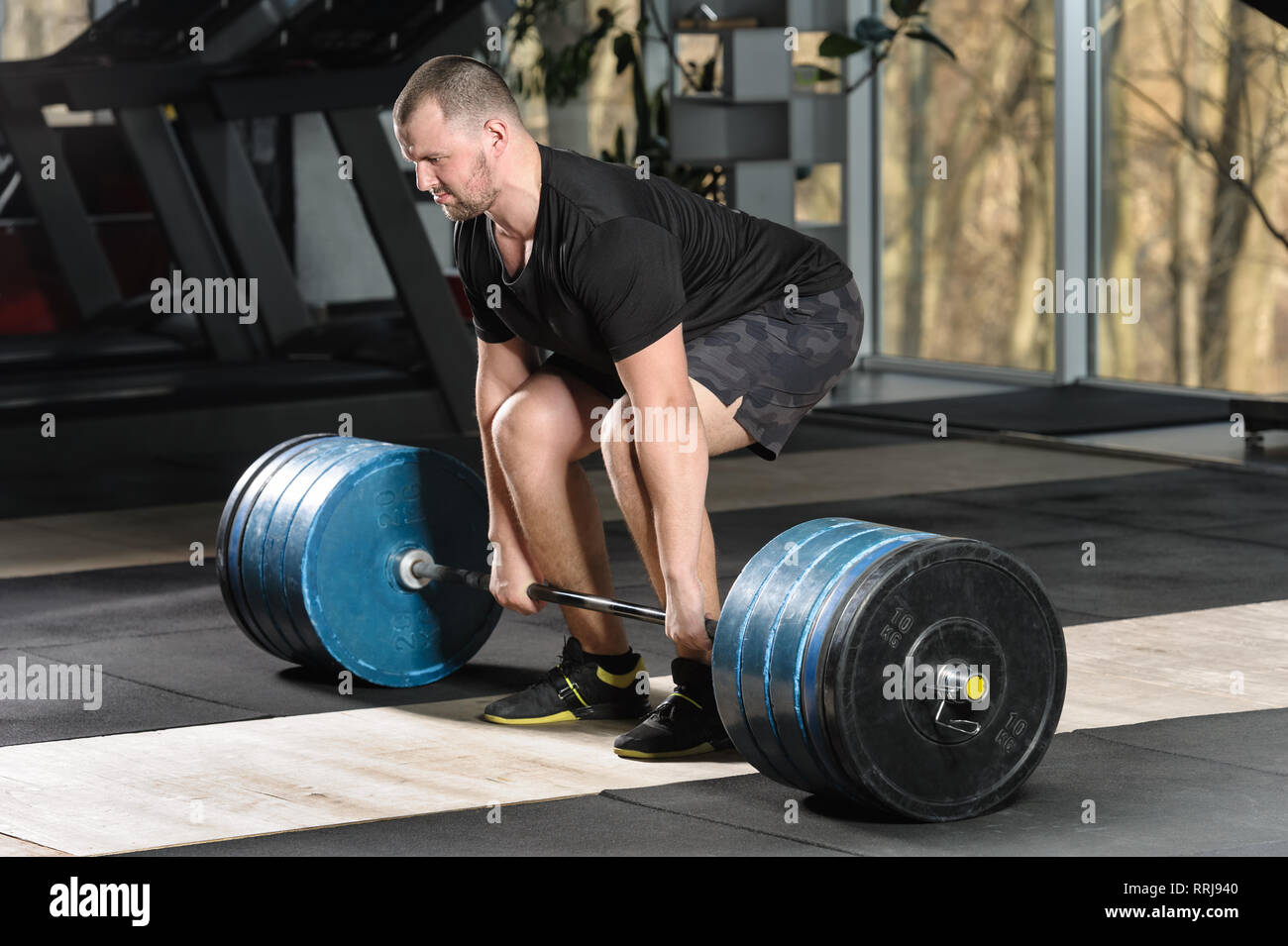 Deadlift attempt. Young man trying to lift heavy barbell Stock Photo