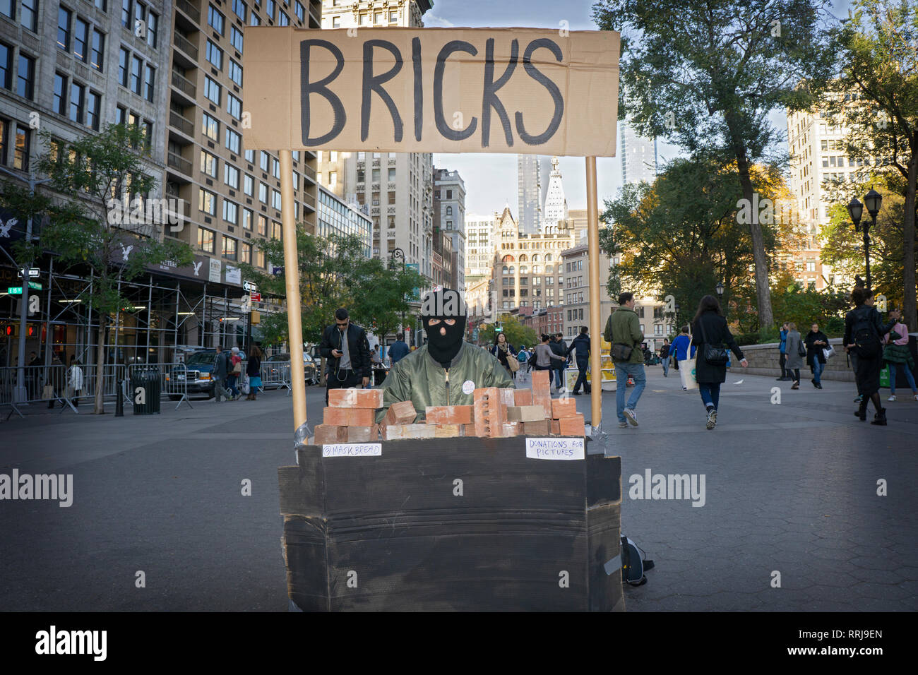 Performance artist Maskbread aka James Mcgann selling bricks in Union Square Park while wearing a ski mask. Stock Photo