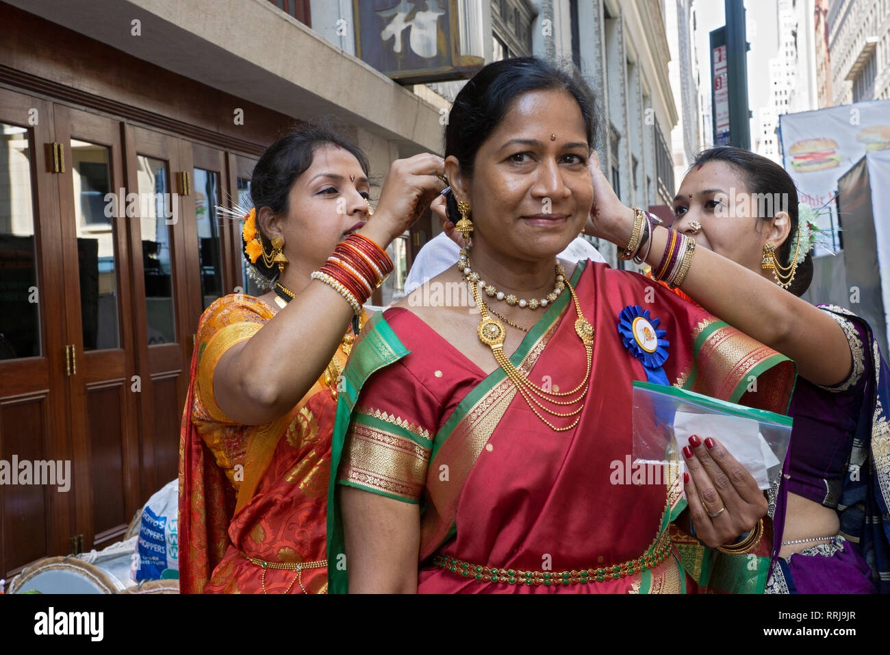 An Indian woman has her hair and jewelry adjusted by two friends just prior to the India Day Parade in Manhattan, New York City. Stock Photo