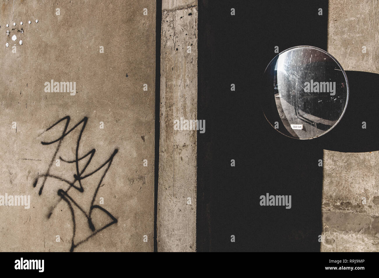 Traffic mirror reflecting back into derelict urban environment - Stock Image