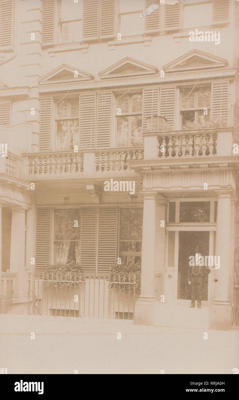 Vintage Photographic Postcard Showing an Edwardian Man Standing in The Doorway of House No 62. Possibly a Guest House Stock Photo