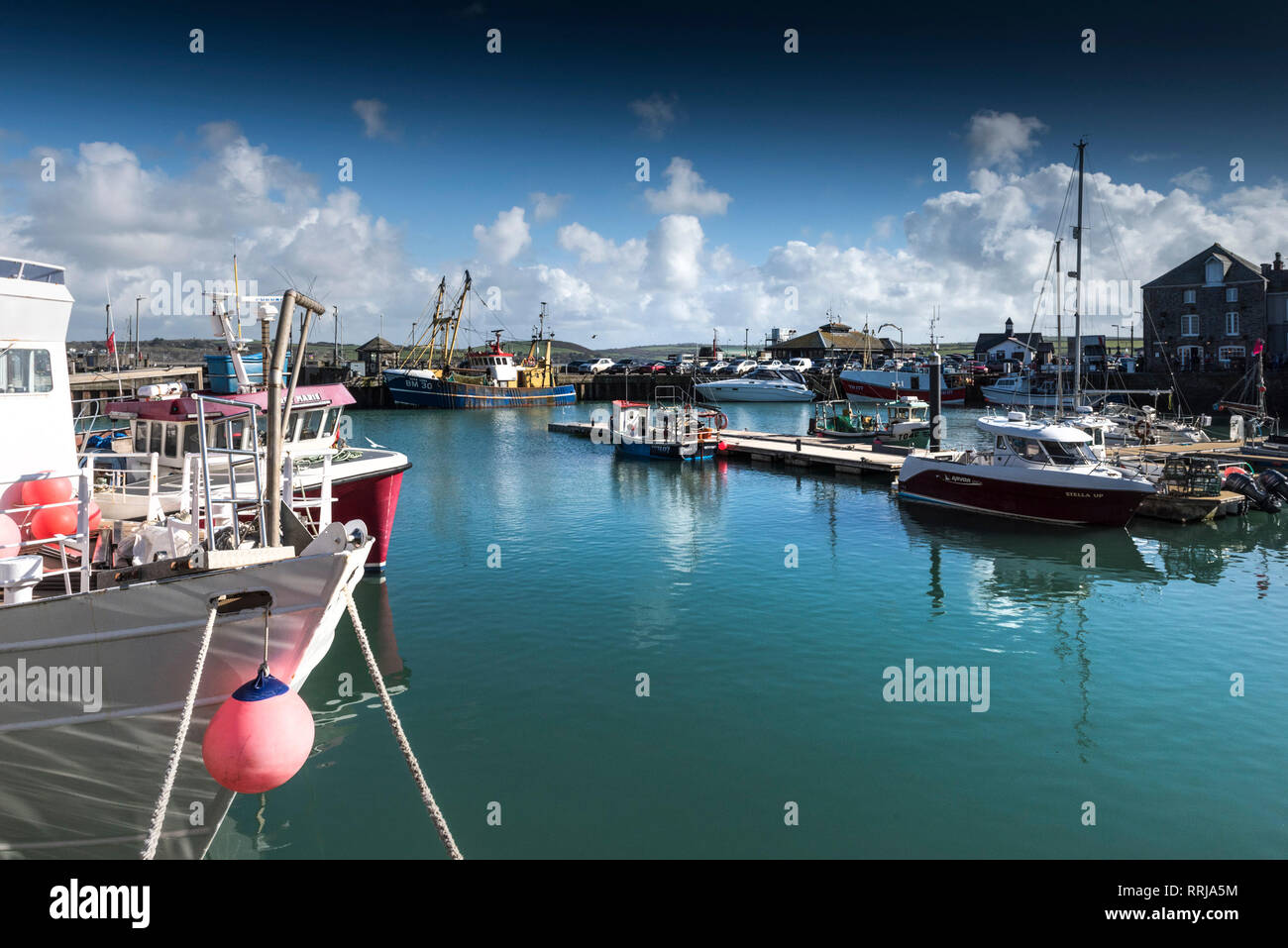 Spring sunshine and blue skies over yachts and fishing boats moored in Padstow Harbour on the North Cornwall coast. Stock Photo