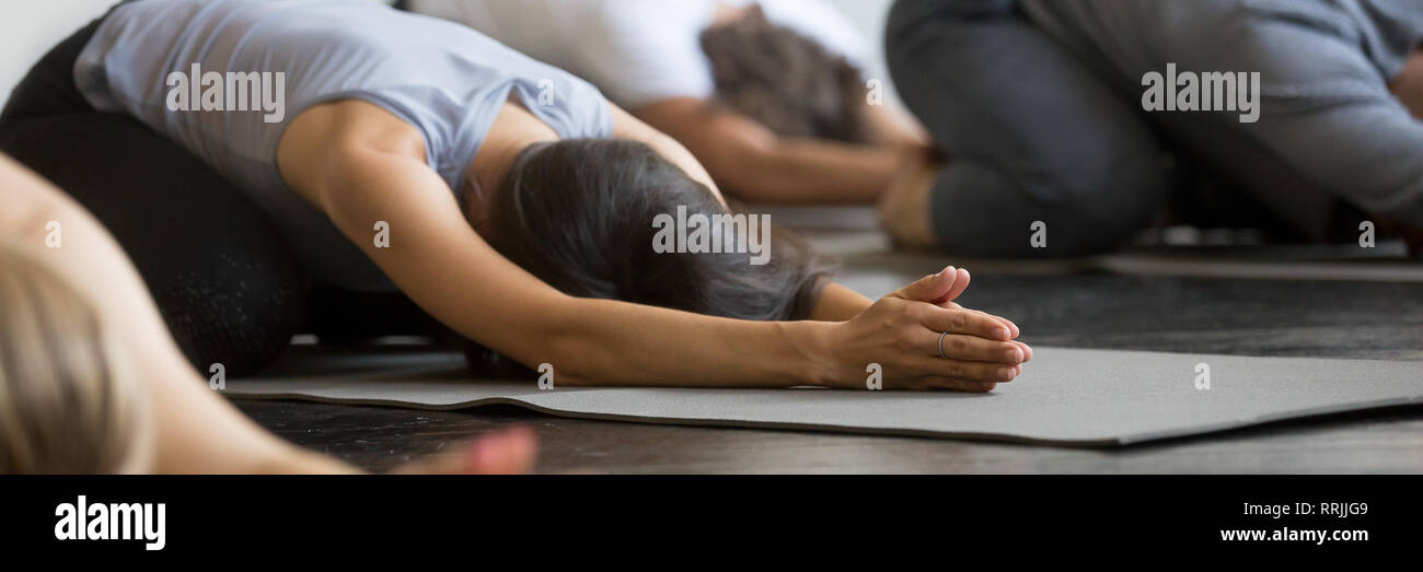 Sporty girls guys practicing Child exercise doing Balasana yoga pose Stock Photo