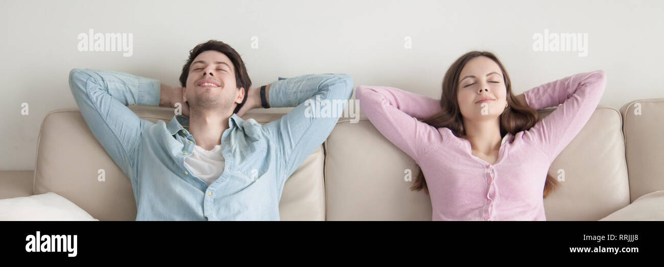 Horizontal image of couple with closed eyes resting on couch Stock Photo