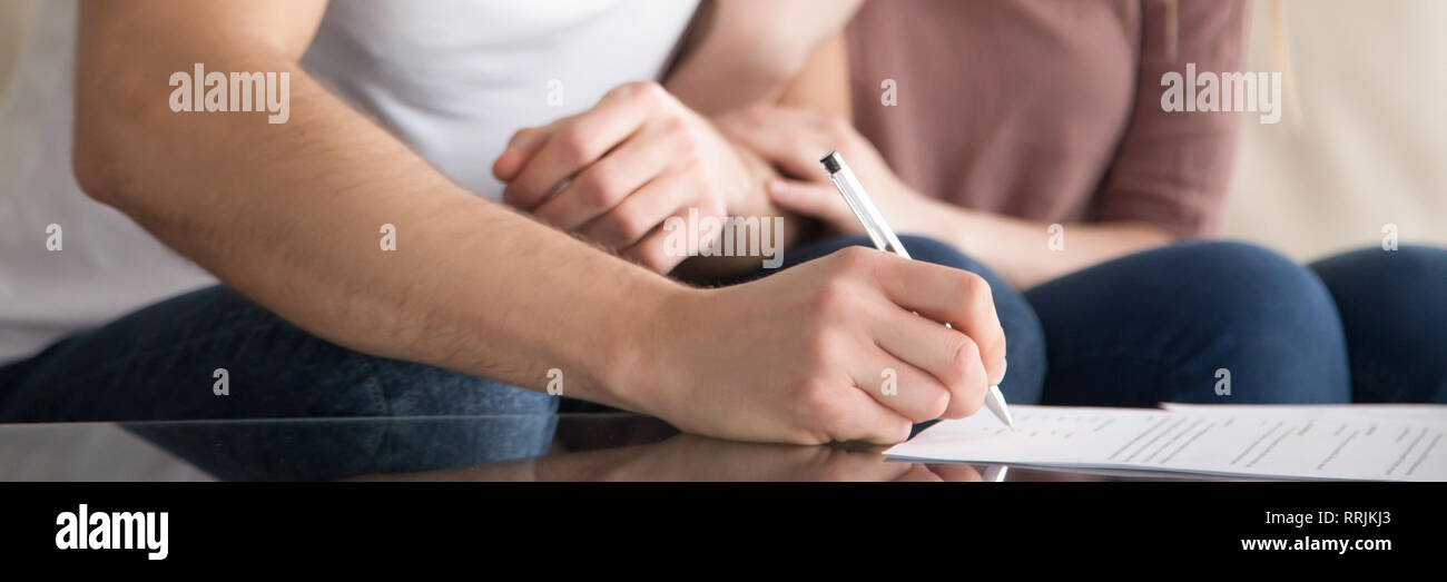 Horizontal photo married couple closeup male hand signing rental agreement Stock Photo