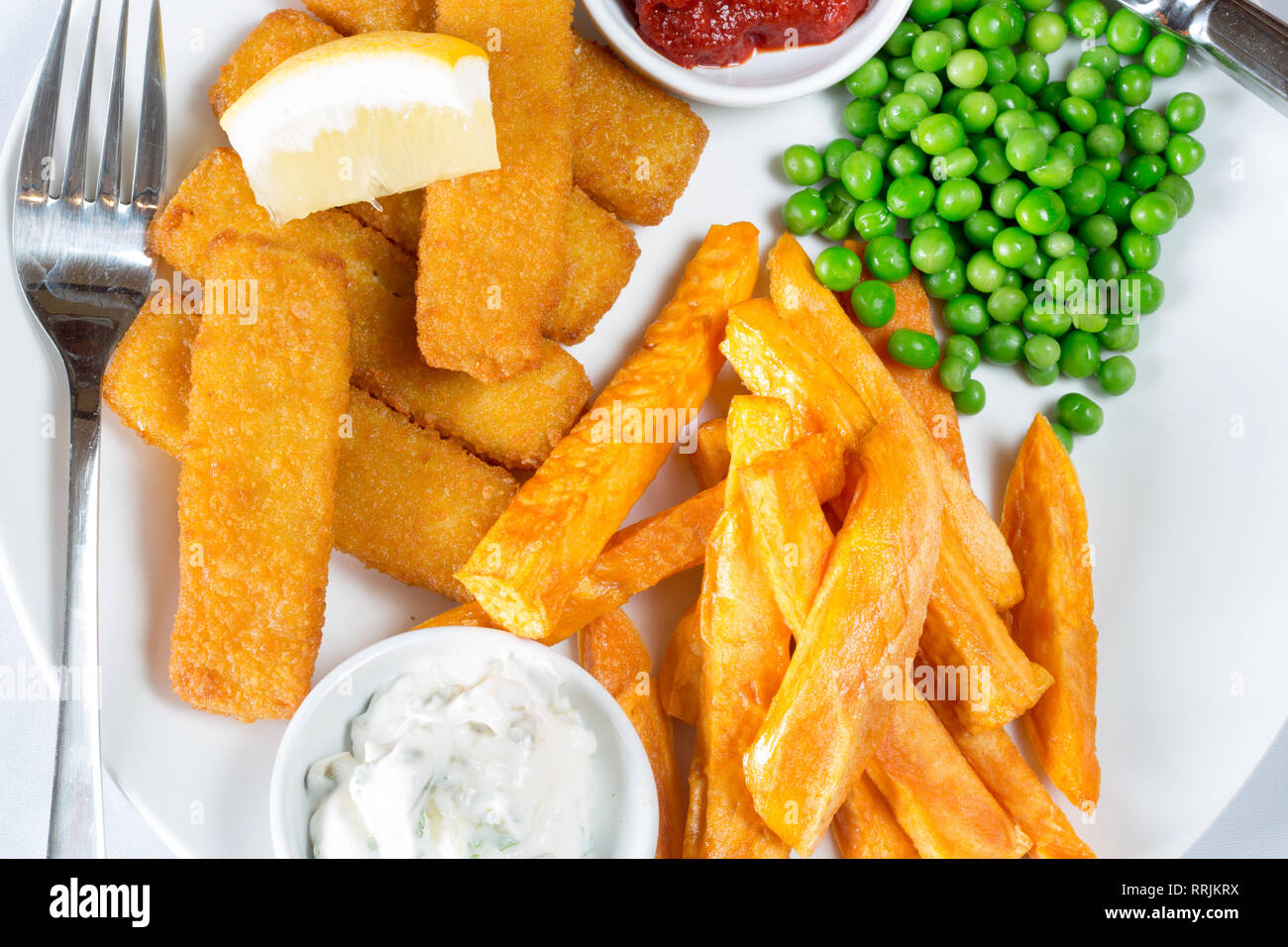 Classic English pub lunch of Fish fingers, chips and garden peas served  with homemade Tomato ketchup, Tartar sauce and fresh Lemon wedge Stock  Photo - Alamy