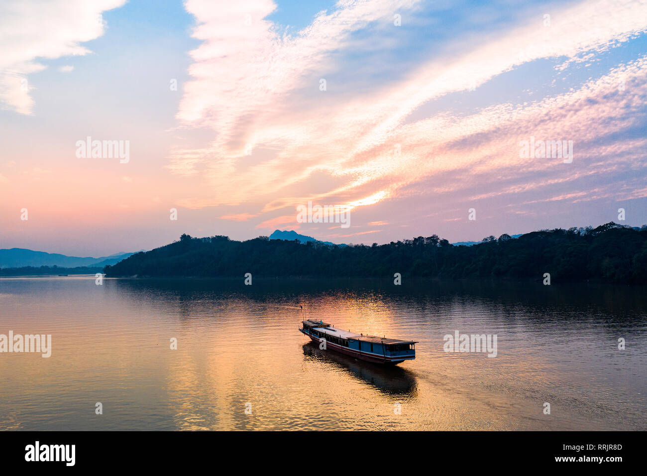 (View from above) Stunning aerial view of a tourists boat sailing on the Mekong river at sunset, Luang Prabang, Laos. Stock Photo
