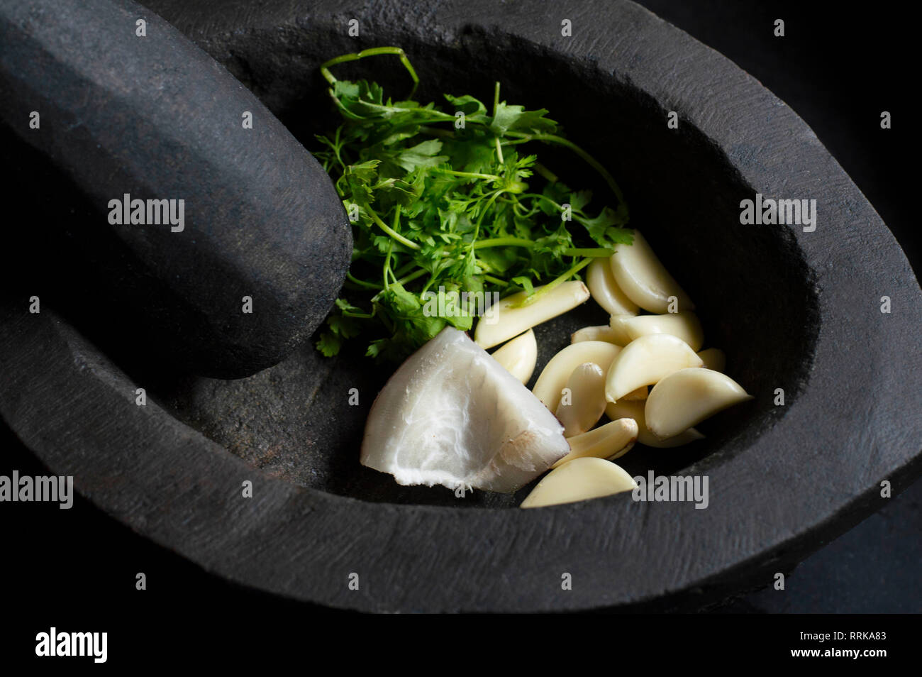 Stone mortar and pestle with garlic, coconut slices and coriander Stock Photo