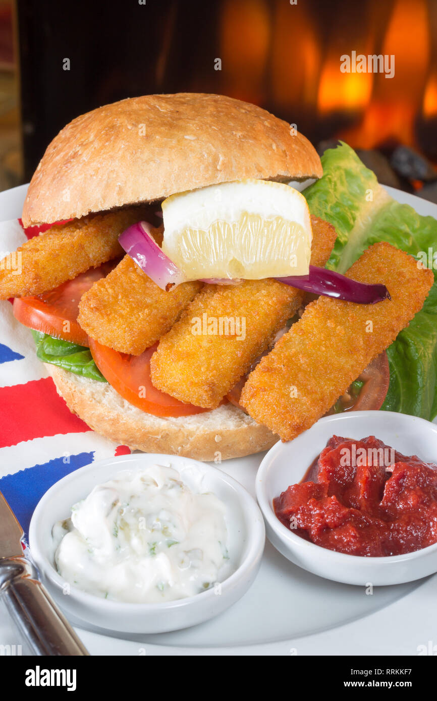 Typical English lunch snack of Fish fingers in a bun with ketchup and Tartar. Stock Photo