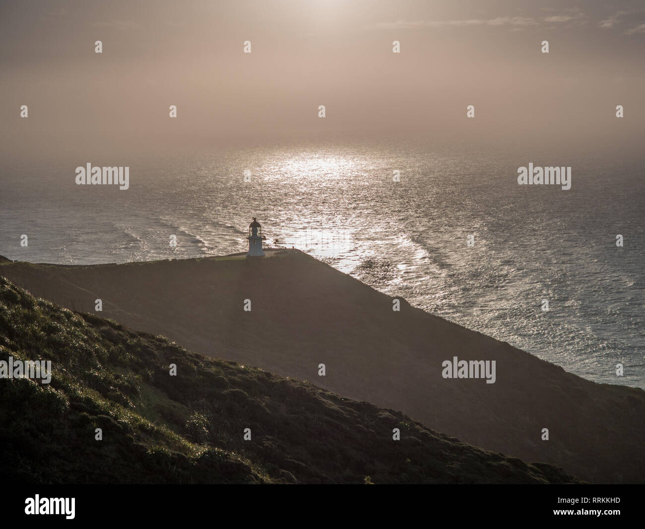 Cape Reinga lighthouse, high above bright sun glare light sea, Northland, New Zealand Stock Photo