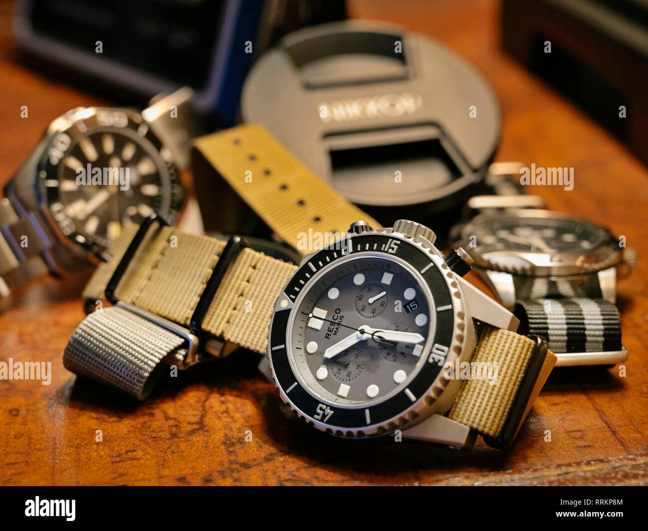 Group of men's luxury diver style wristwatches or timepieces on a dark wood background. Stock Photo