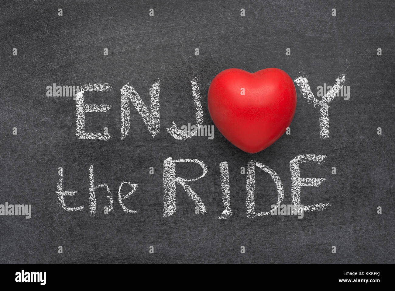 enjoy the ride phrase handwritten on blackboard with heart symbol instead of O Stock Photo