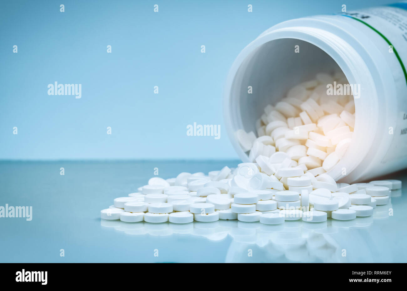 White tablets pill spilled out from white plastic bottle container. Pharmaceutical industry. Pharmacy product. Global healthcare. Drug use in hospital Stock Photo