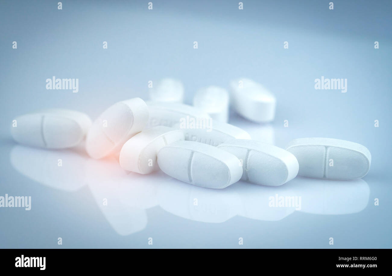 Pile of white oblong tablets pills on gradient background. Pharmaceutical industry. Pharmacy product. Global healthcare. Drug in pharmacy drugstore Stock Photo