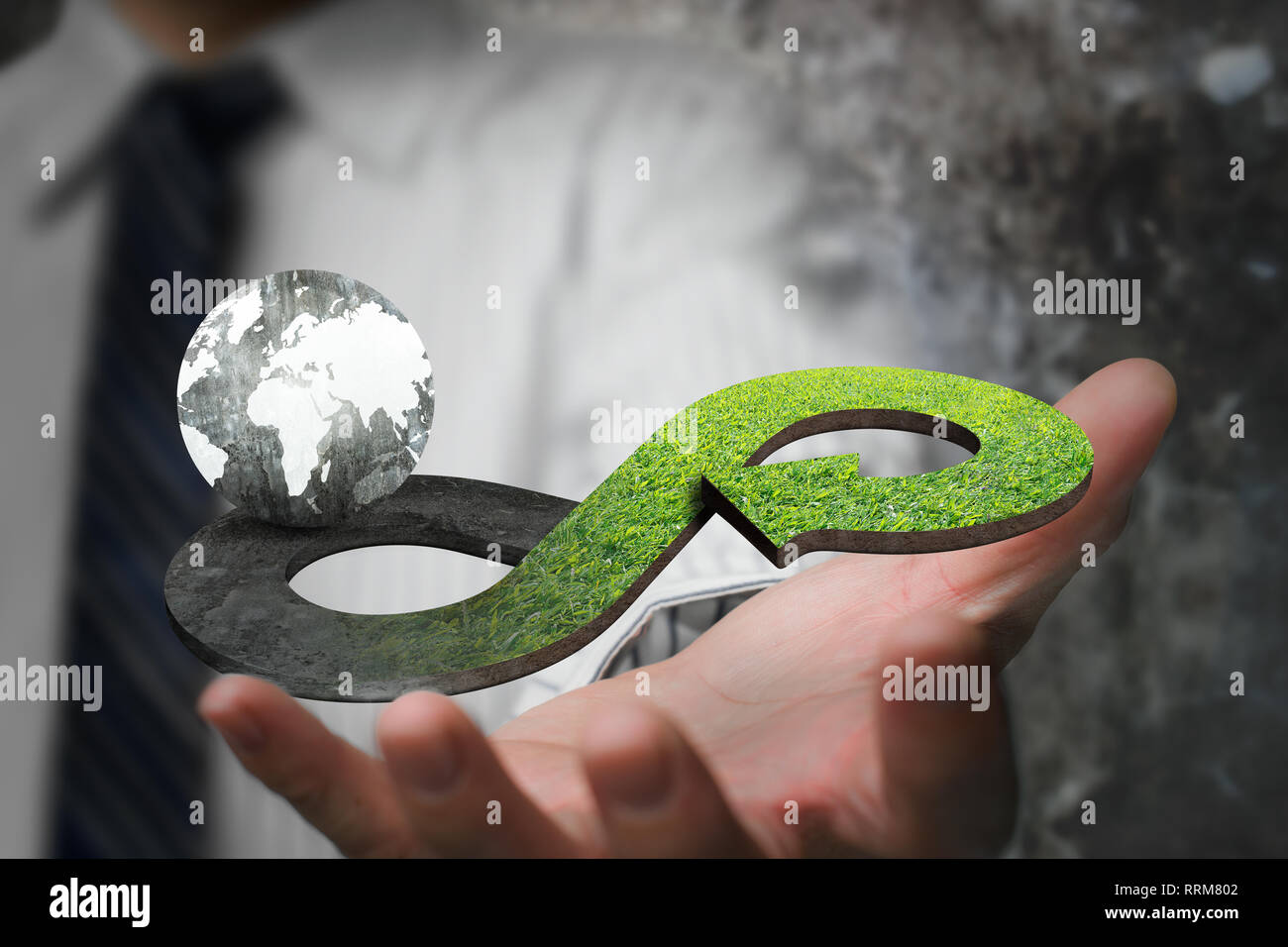 Green circular economy concept. Hand showing arrow infinity symbol with grass texture and globe. Stock Photo