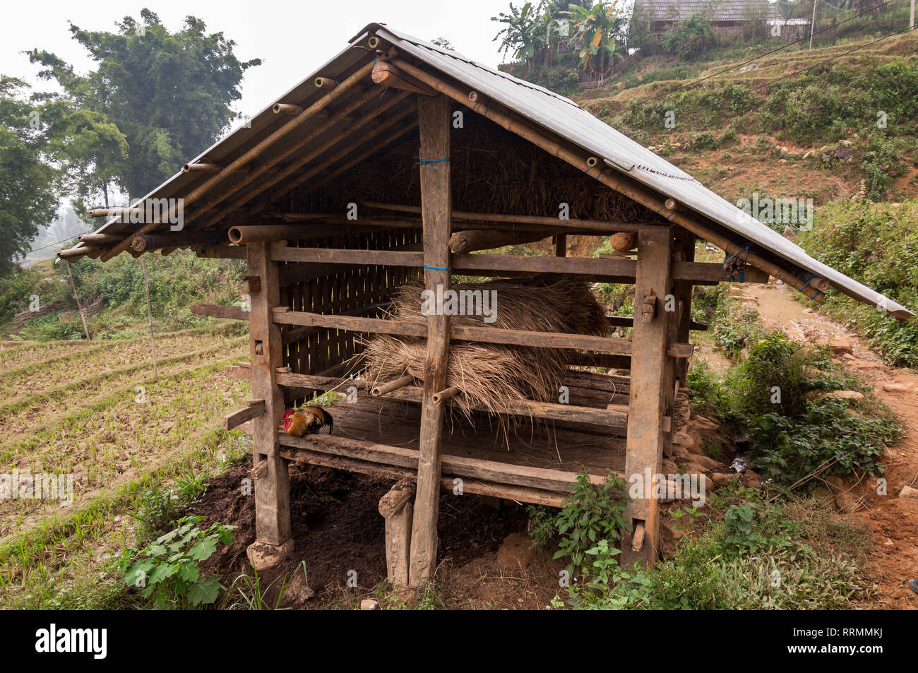 Hay bales stored in an outdoor wooden store by fields on a foggy day ...