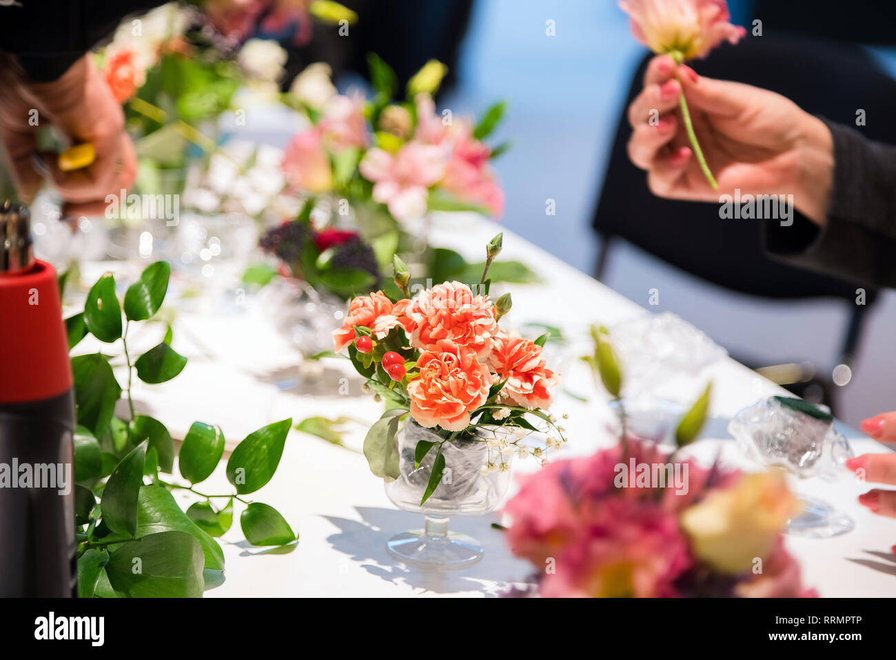 Closeup of hands of young woman florist creating bouquet of pink flowers on the table Stock Photo