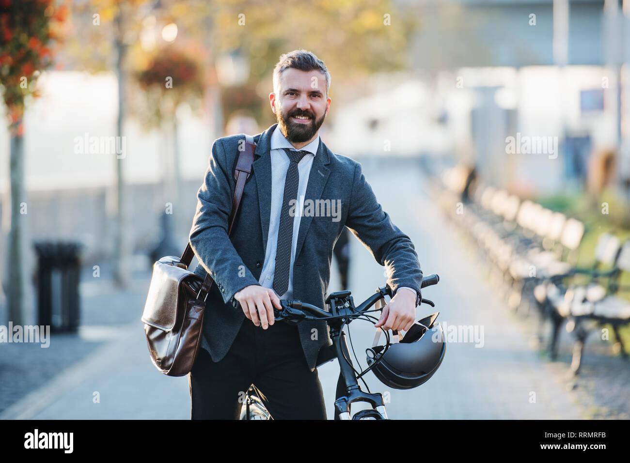 A businessman commuter with bicycle walking home from work in city. Stock Photo