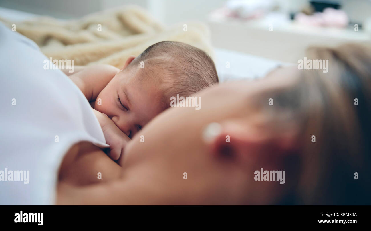 Newborn lying on the bed with her mother Stock Photo