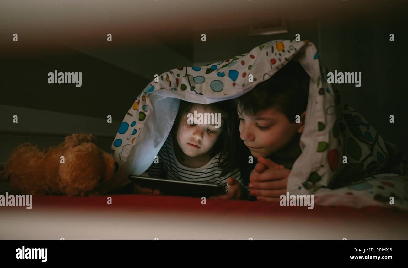 Brothers looking at the tablet in the dark Stock Photo