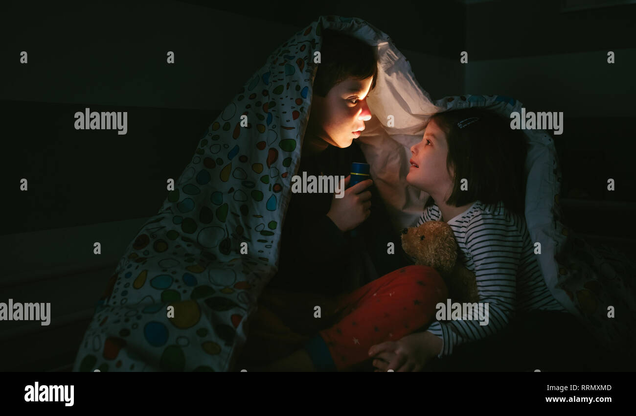 Boy telling a story of fear to his sister Stock Photo