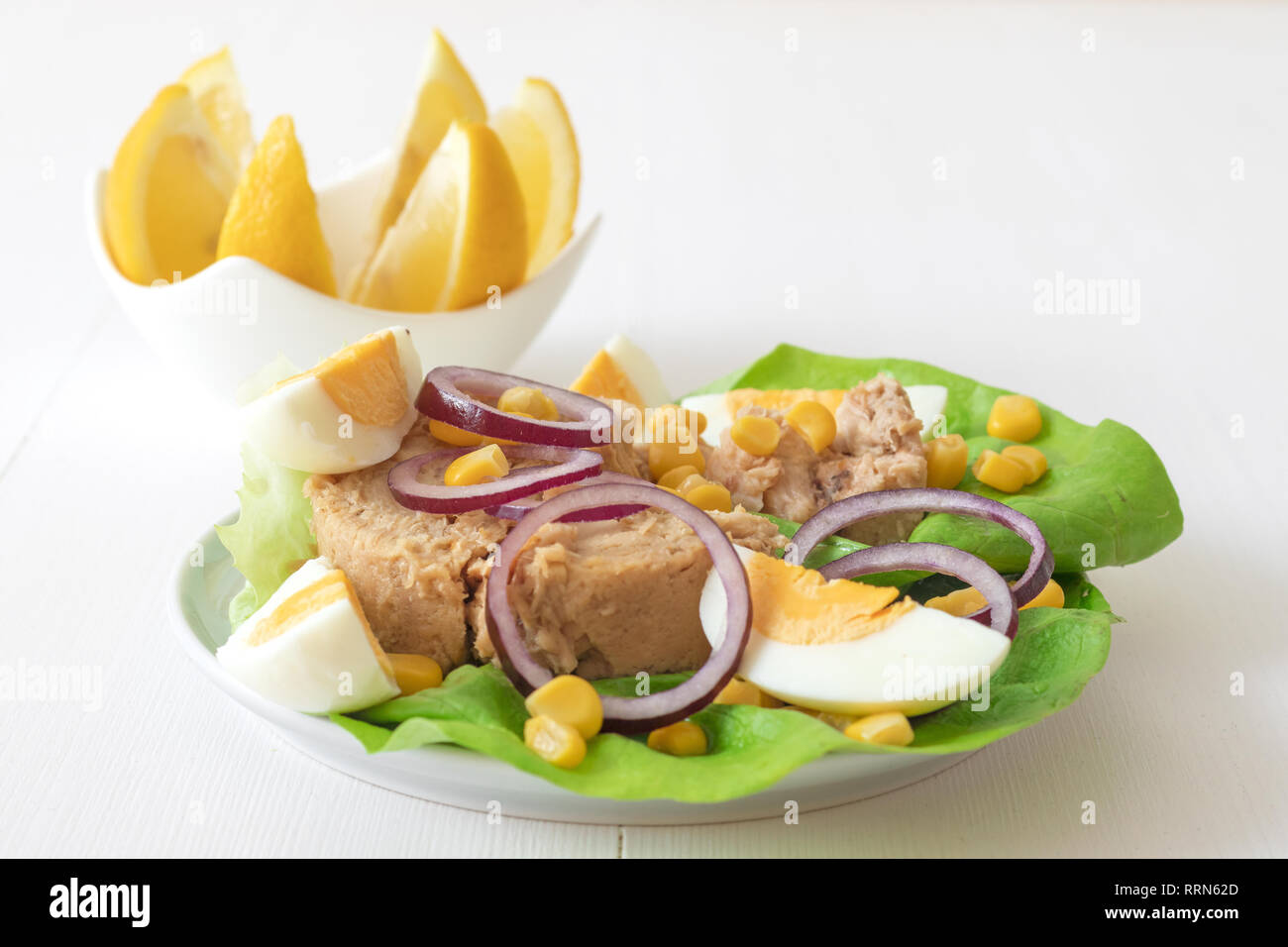 Canned tuna with eggs, suggar corn, red onion rings on green lettuce
