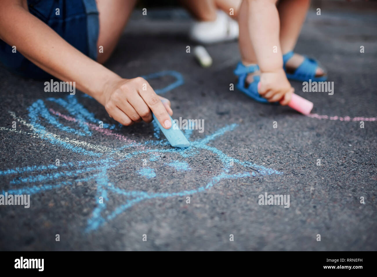 Close up of little girl drawing with chalks on the sidewalk. Kids ...