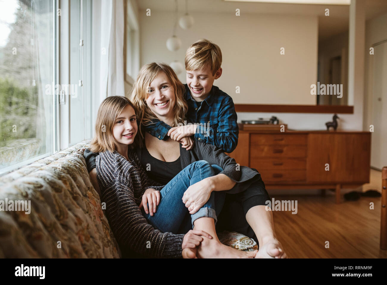 Portrait happy mother and children cuddling on living room sofa Stock Photo