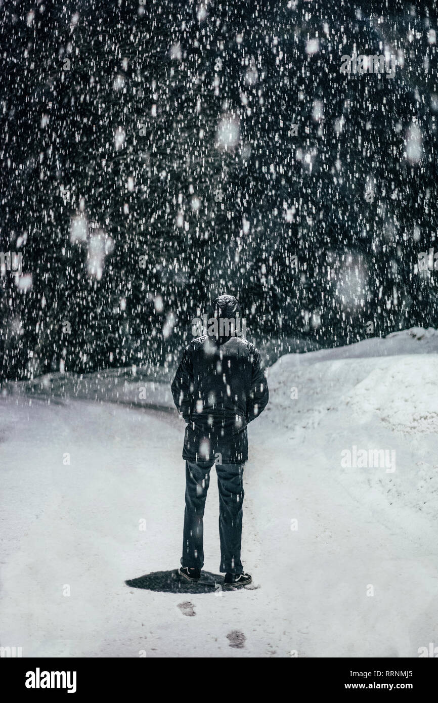 Snow falling over man Stock Photo