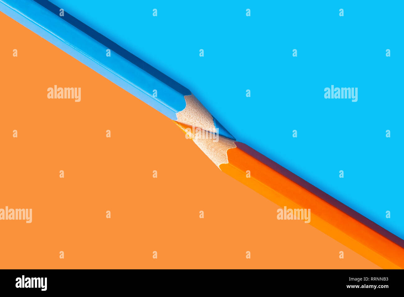 Orange and blue pencils located diagonally on a two-color background Stock Photo